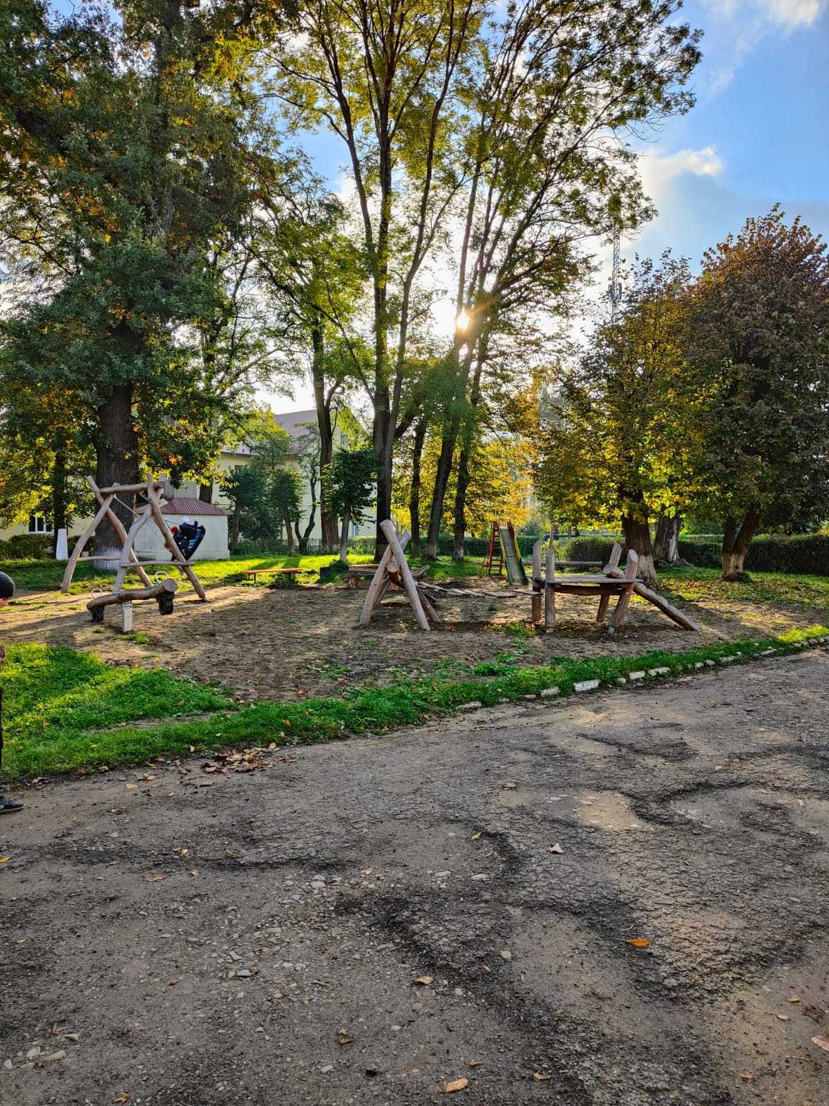 Sonniger Spielplatz mit Holzschaukeln und grünen Bäumen